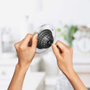 Hands pressing central knob on OXO sink strainer to show flexible silicone basket design