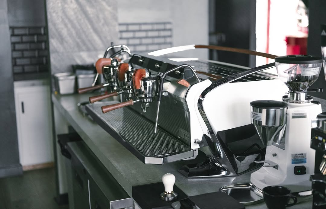 Professional espresso machine on a counter next to a commercial grinder