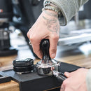 Barista tamping coffee grounds with Compressore 58mm convex tamper on portafilter