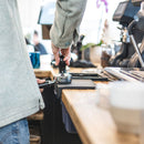 Barista using Compressore black tamper on wooden counter with coffee machine