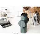 Dark green Pietro Pro manual coffee grinder in use pouring beans into filter setup