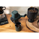 Dark green Pietro Pro manual coffee grinder with removed hopper revealing grounds