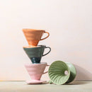Stacked Hario V60 ceramic drippers in orange, green, and pink