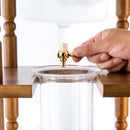 Hand adjusting gold metal spigot to control drip flow on Yama cold brew tower